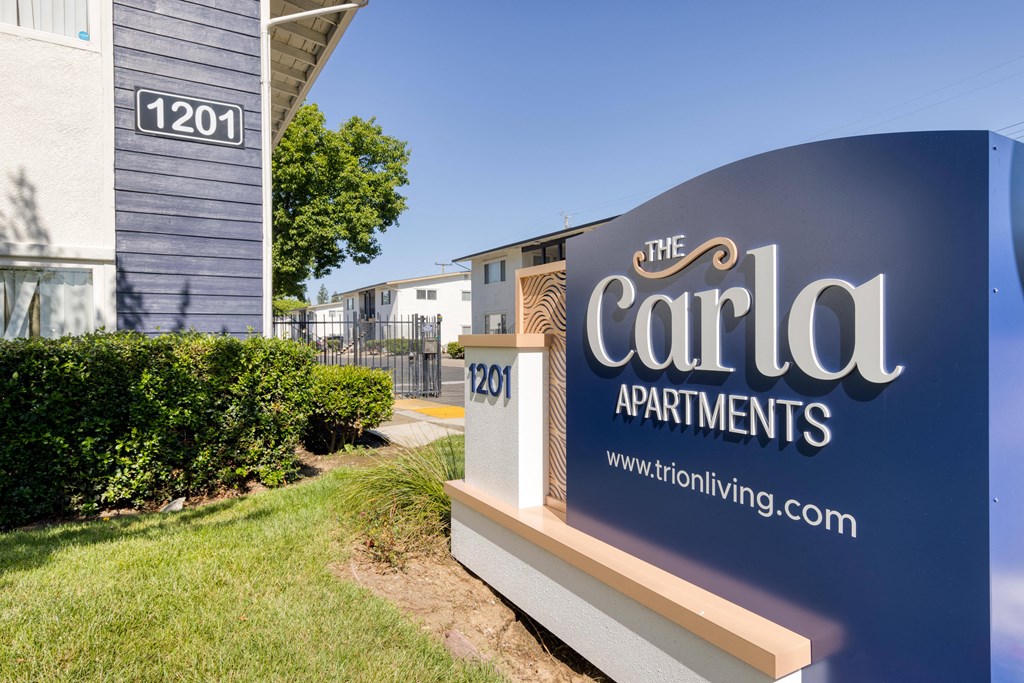 a sign that says the carla apartments with a building in the background
