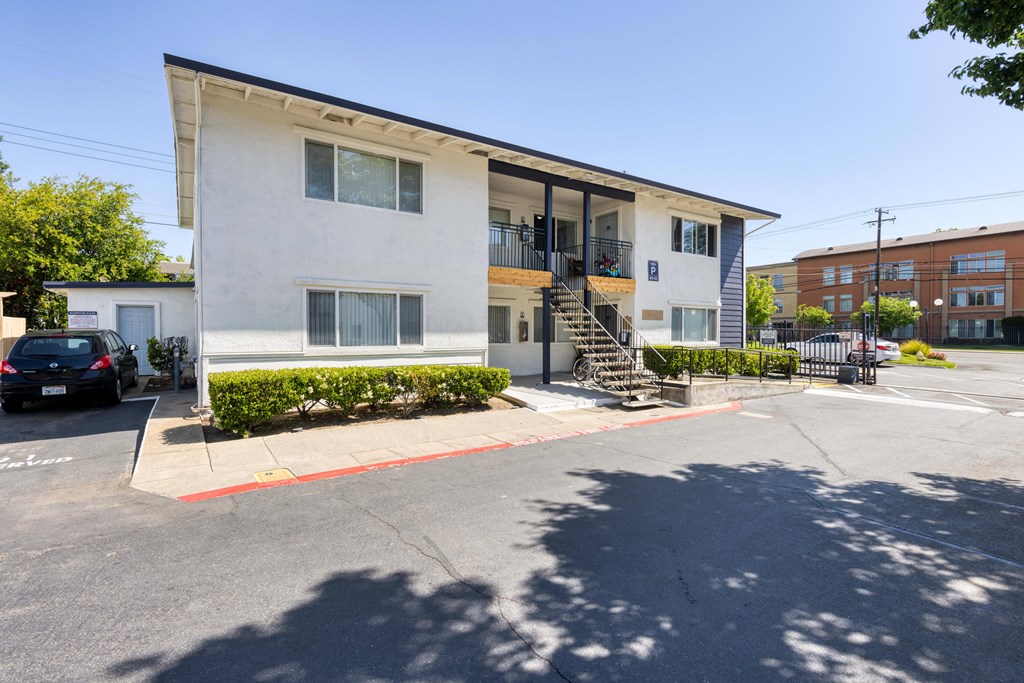 a white apartment building with a black car parked in front of it