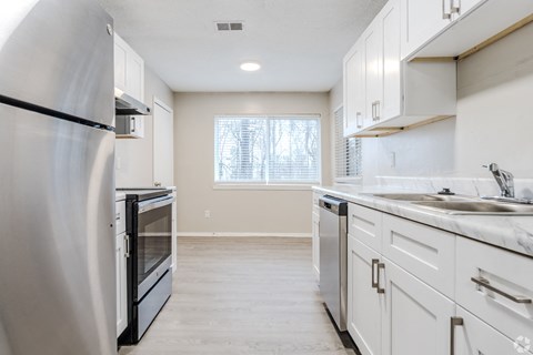 A kitchen with white cabinets and a black fridge.