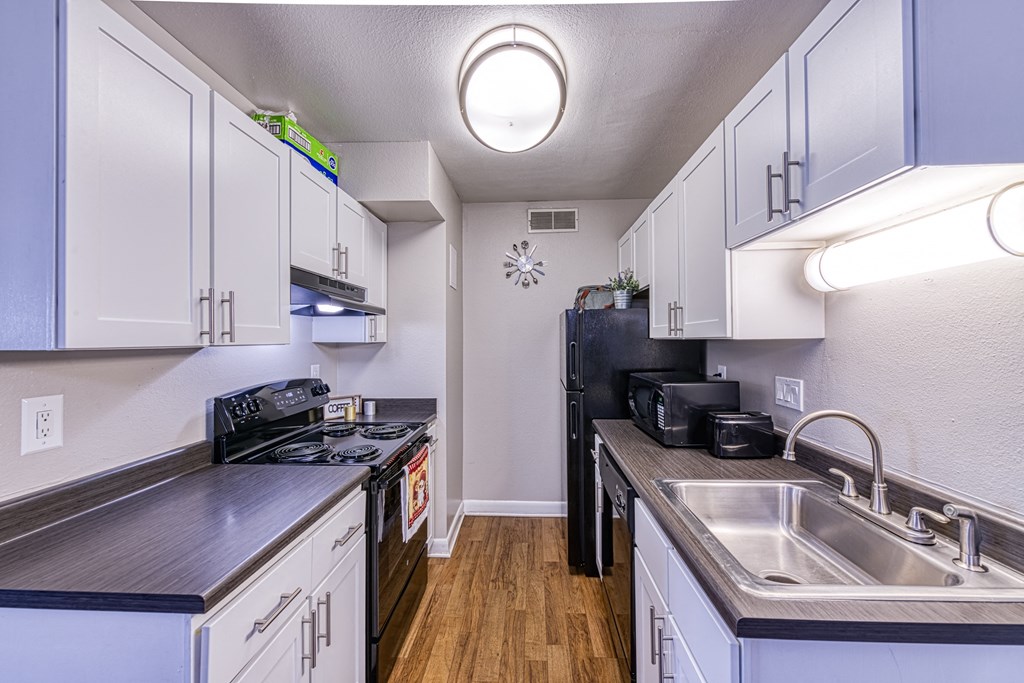a kitchen with white cabinets and black appliances