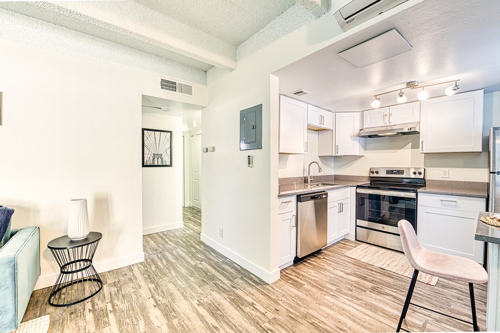 a kitchen and living room with white walls and wood flooring