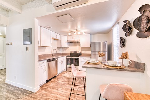 a kitchen with white cabinets and stainless steel appliances and a table with chairs