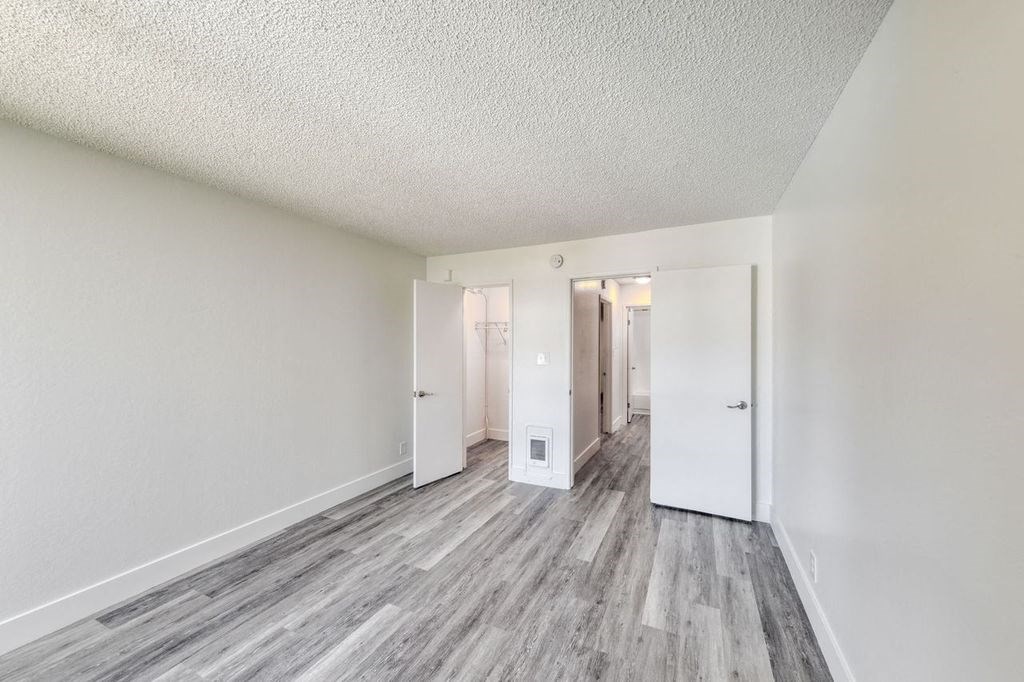 a bedroom with hardwood floors and white walls