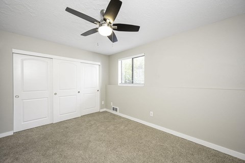 a bedroom with a ceiling fan and two closets