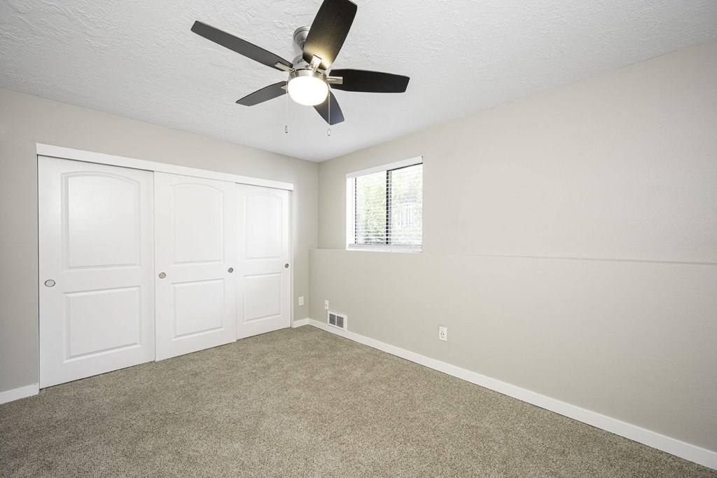 a bedroom with a ceiling fan and two closets