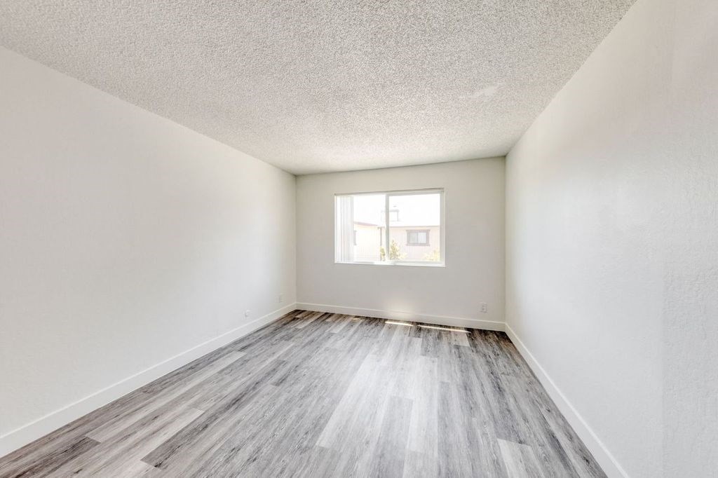a bedroom with hardwood floors and white walls