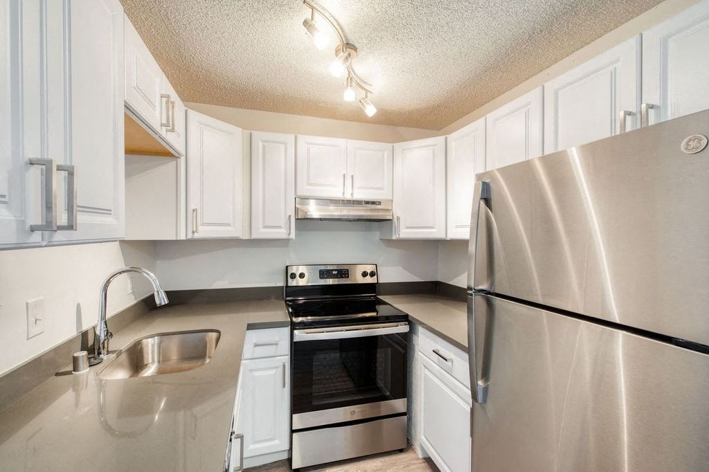 a kitchen with white cabinets and stainless steel appliances