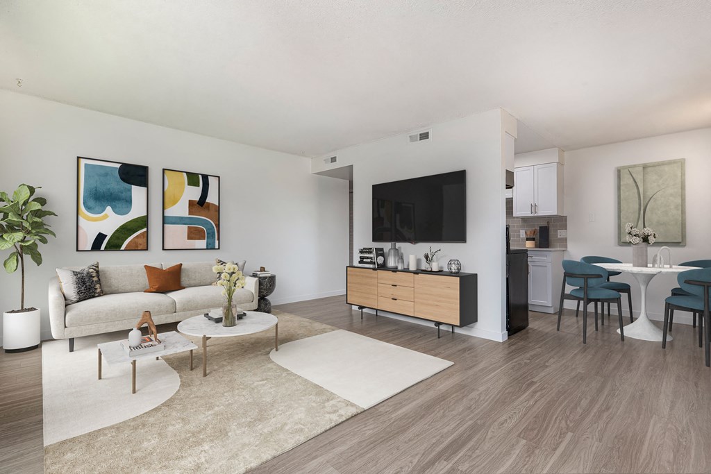 A living room with a white couch, a coffee table, a TV, and a dining table with chairs.