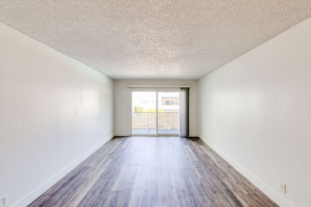 an empty living room with white walls and wood floors
