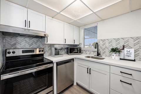 a kitchen with white cabinets and black and white appliances