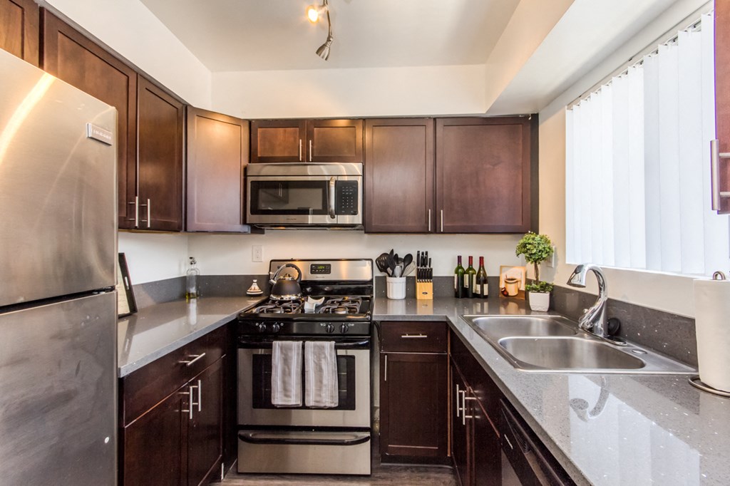 a kitchen with dark wood cabinets and stainless steel appliances