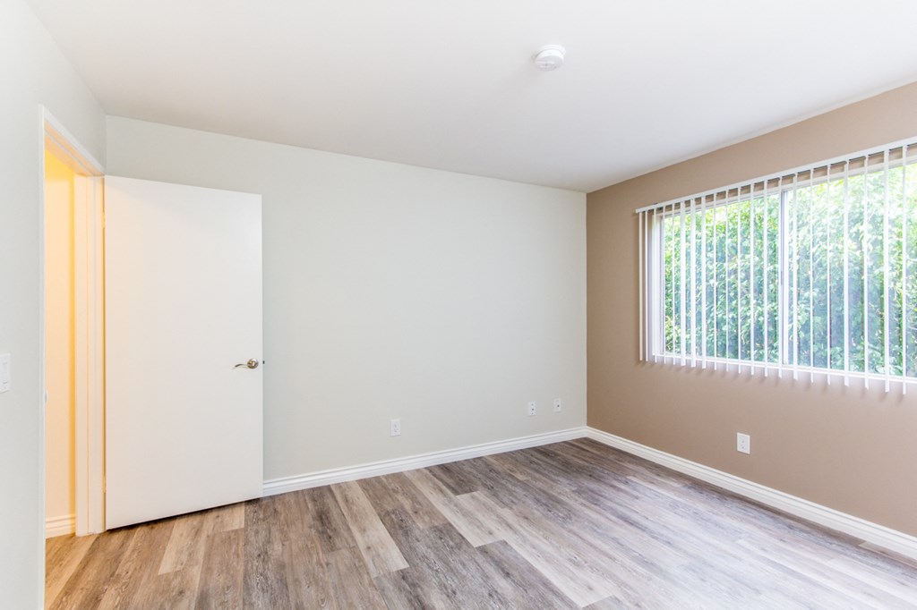 a bedroom with hardwood floors and a large window