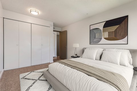 A bedroom with a large bed and a painting on the wall.