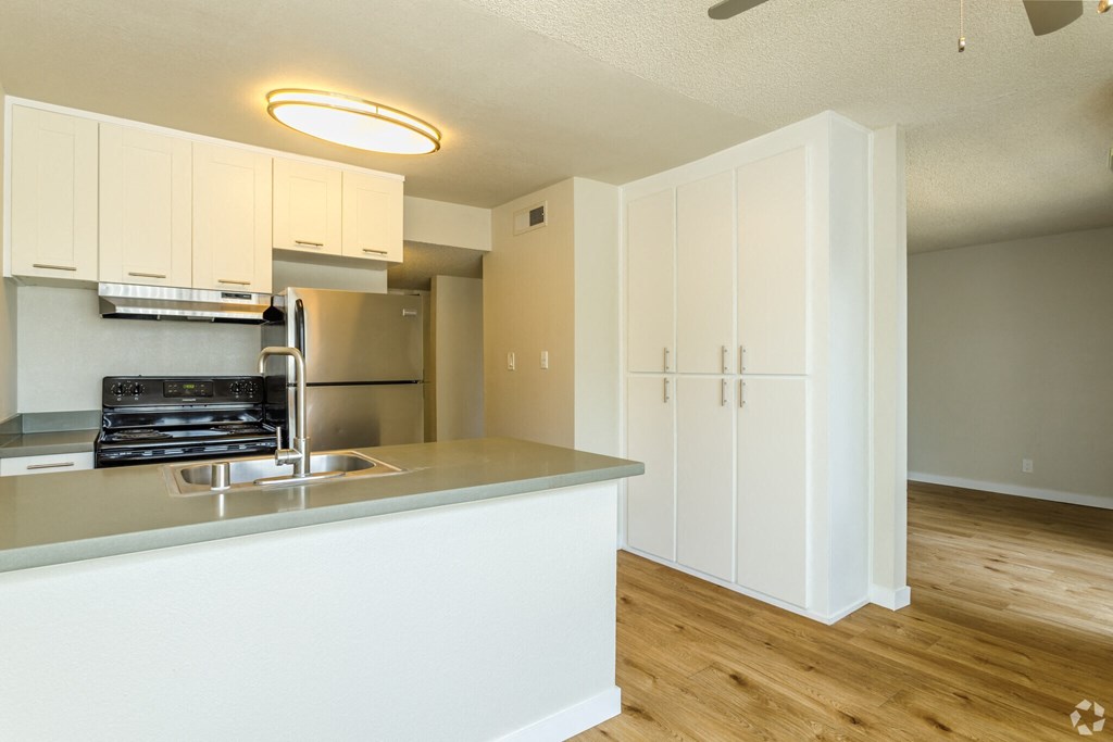 an empty kitchen with white cabinets and a stainless steel refrigerator and sink