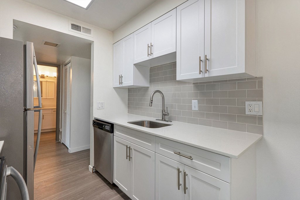 A kitchen with white cabinets and a grey backsplash.