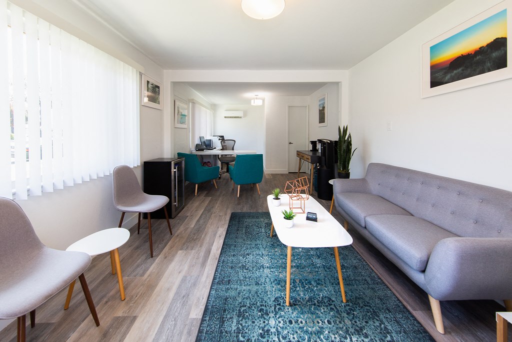 a living room with a couch coffee table and chairs and a dining room table in the background