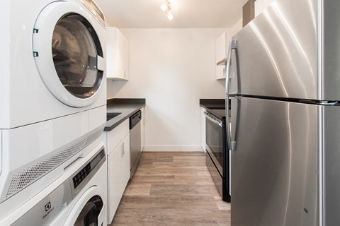 a washer and dryer in a kitchen with a stainless steel refrigerator