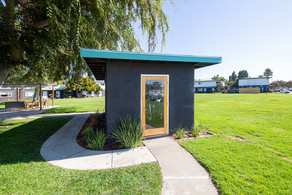 a small black building with a glass door and a green roof