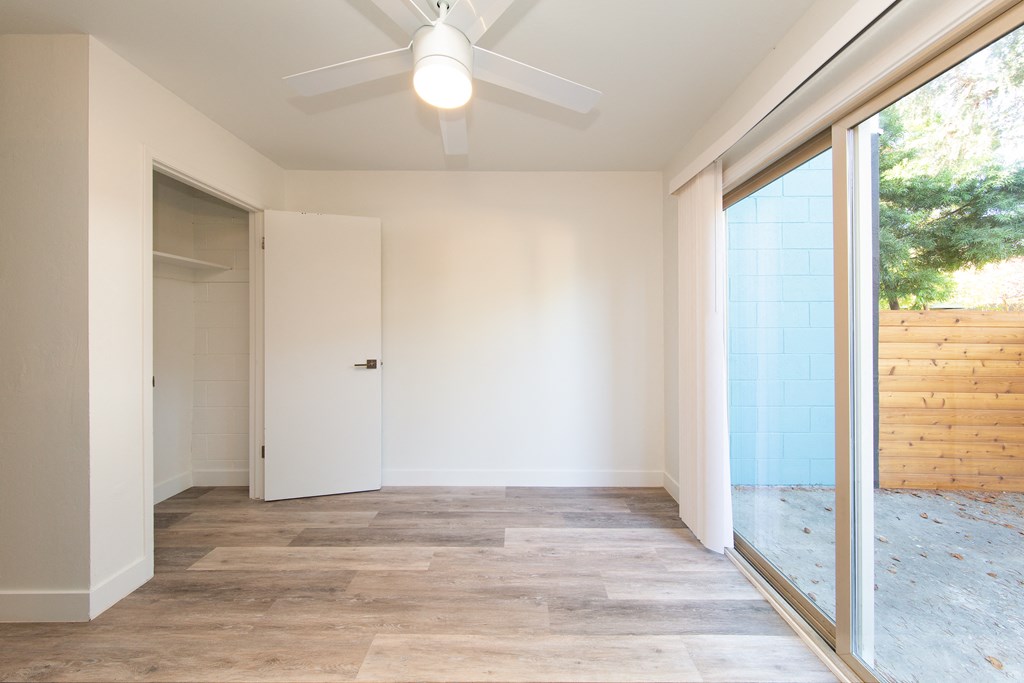 a bedroom with a ceiling fan and a sliding glass door