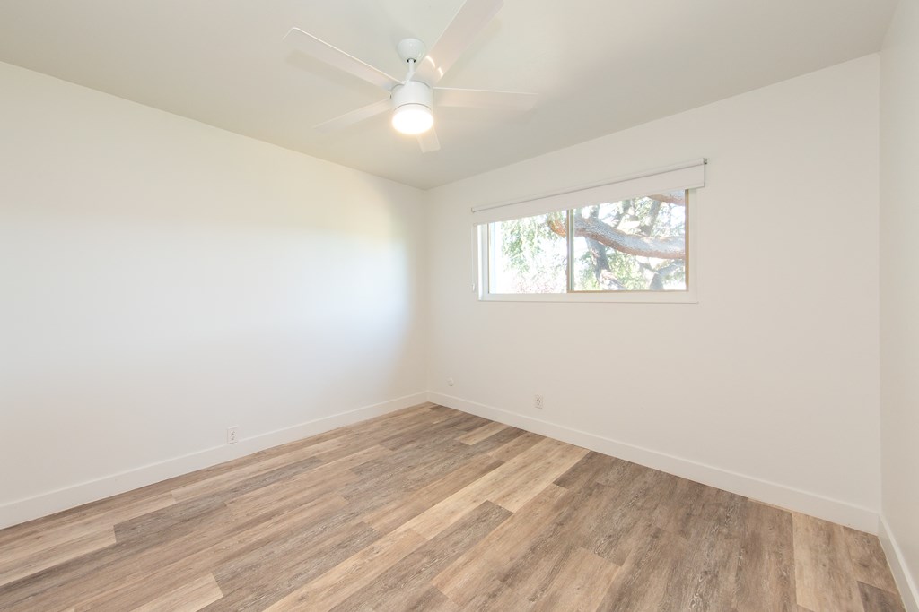an empty room with a ceiling fan and a window