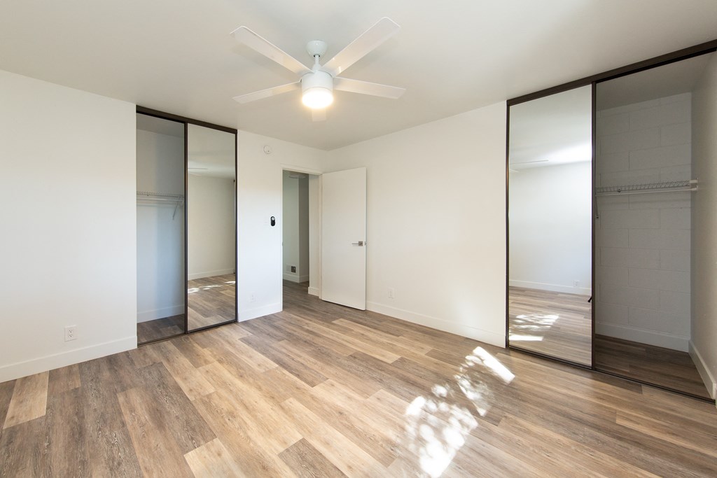 a bedroom with white walls and a ceiling fan