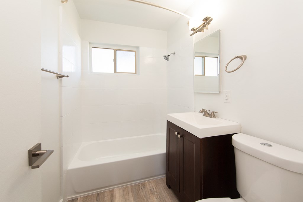 a bathroom with white walls and a white toilet next to a white sink and bathtub