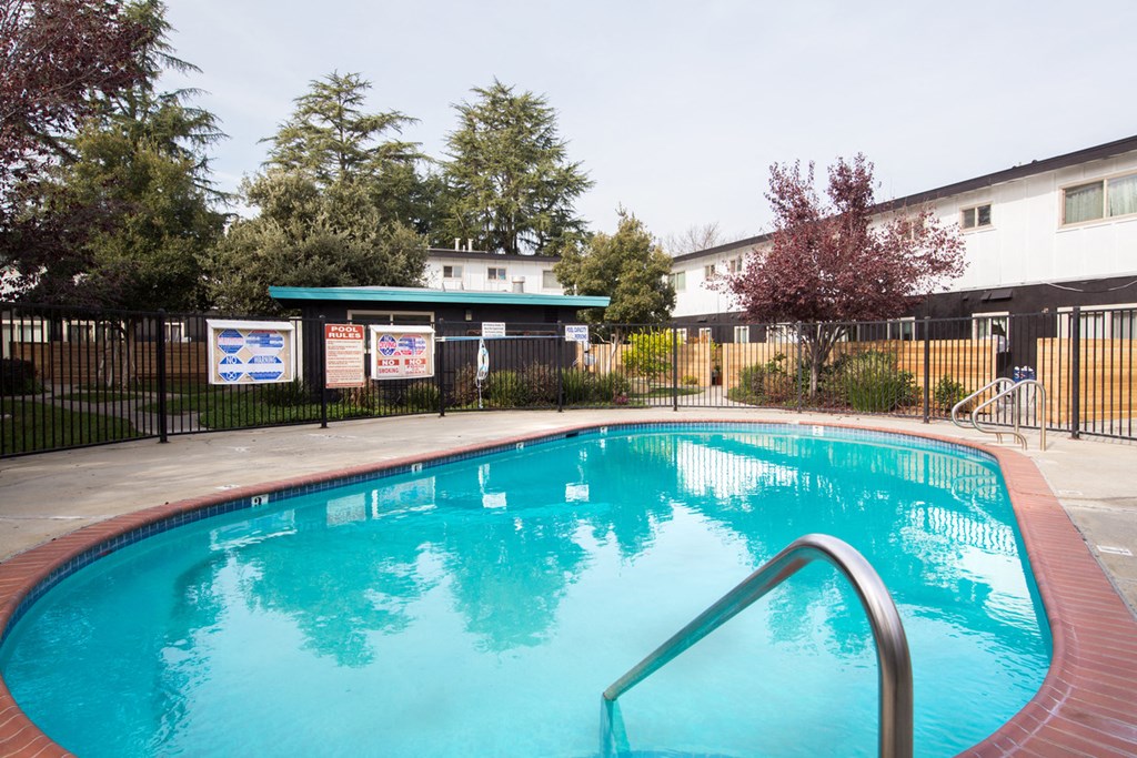 a swimming pool with a fence and buildings in the background