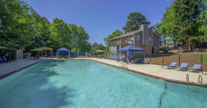 a swimming pool with chaise lounge chairs and umbrellas in front of a brick building