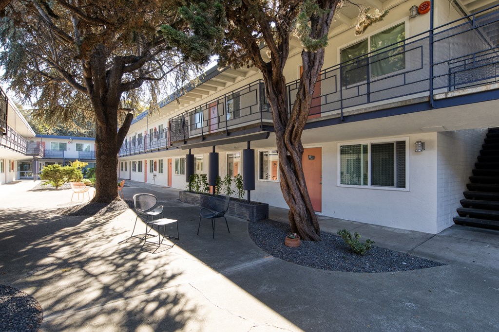 a courtyard with trees and a staircase in front of a building