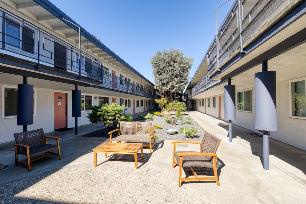 a courtyard with chairs and tables on a sunny day