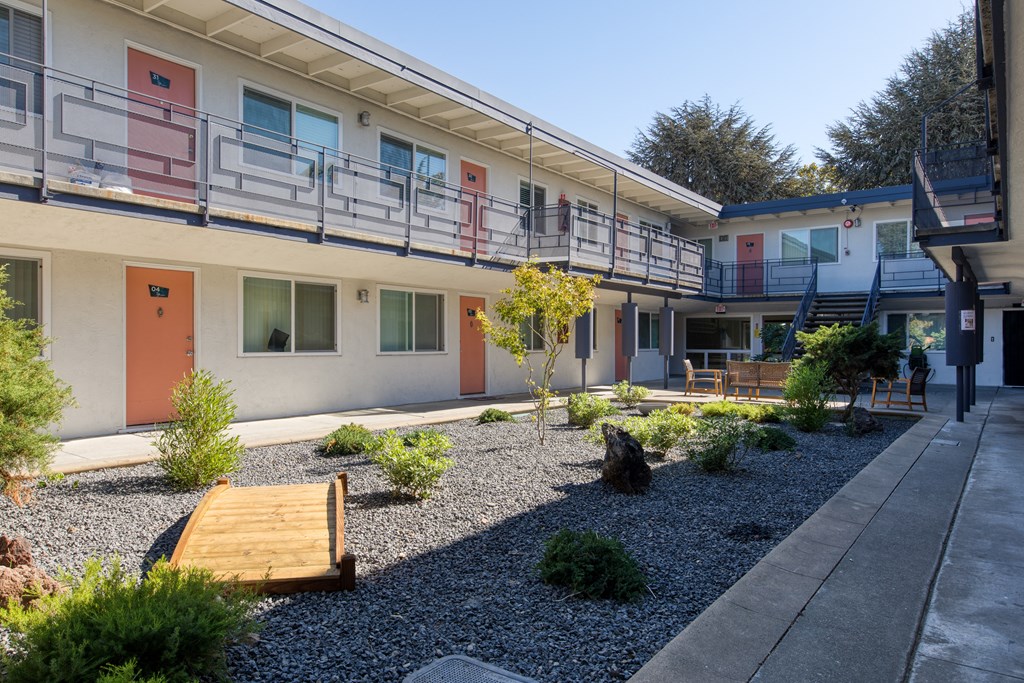 a courtyard with benches and plants in front of a building