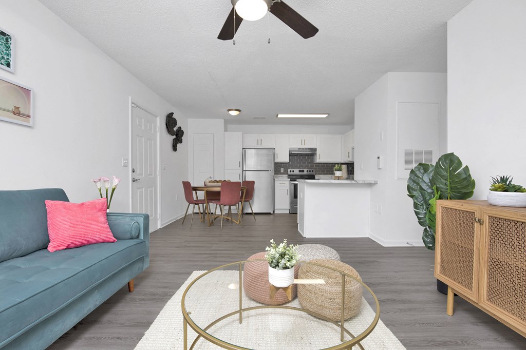 a living room with a couch a coffee table and a kitchen in the background