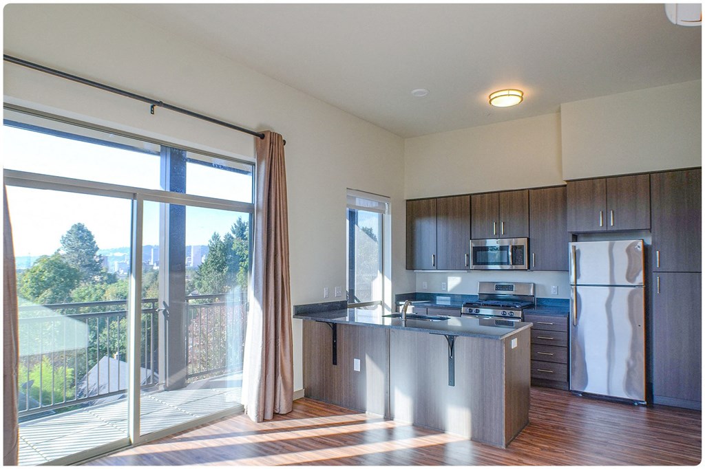 a kitchen with a large sliding glass door leading to a balcony