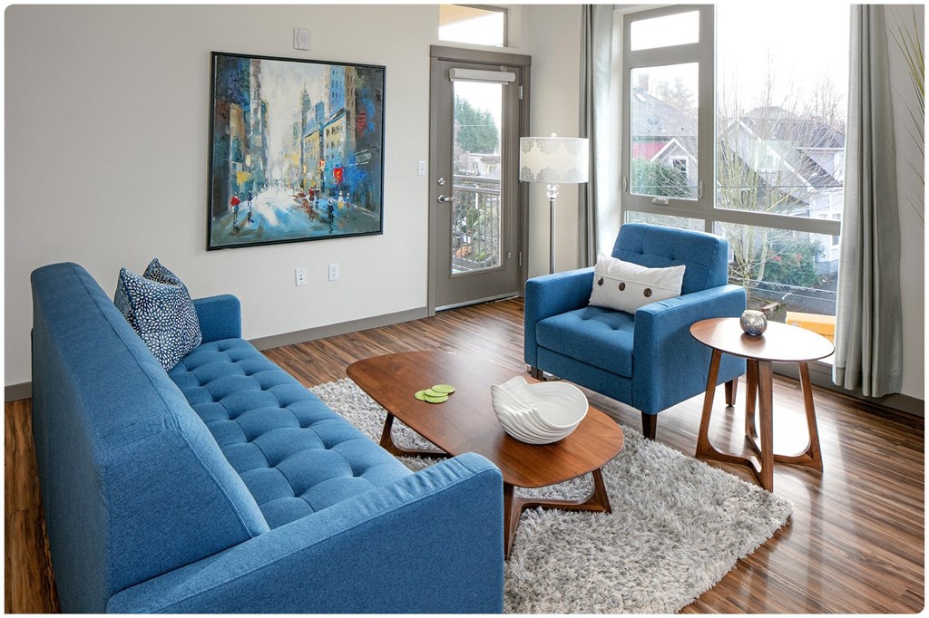 a living room with blue furniture and a large painting on the wall