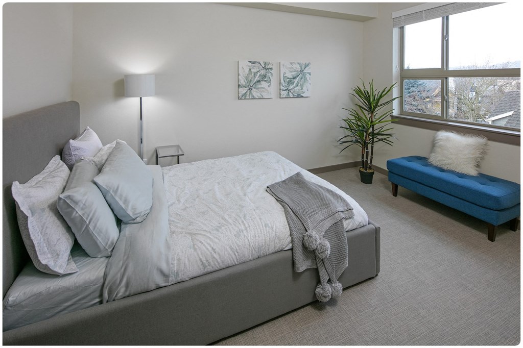 a bedroom with a large bed and a blue chaise lounge