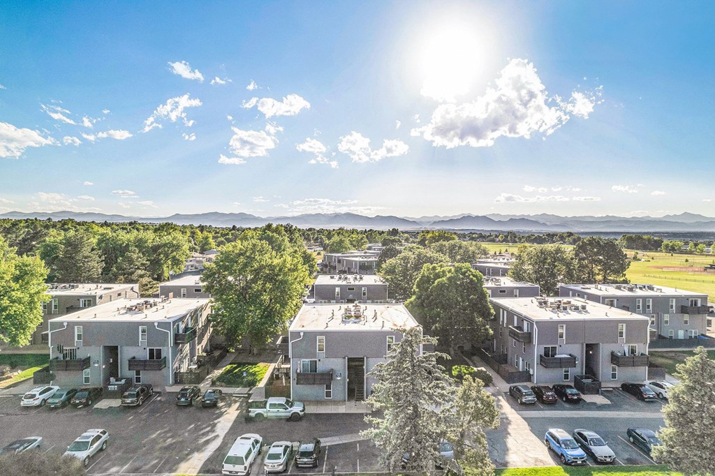 A sunny day at a residential complex with cars parked in the lot.