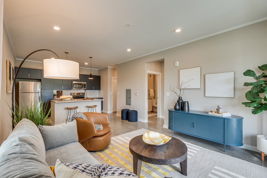 a living area with a couch coffee table and a kitchen in the background