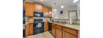 a kitchen with black appliances and granite counter tops and wooden cabinets