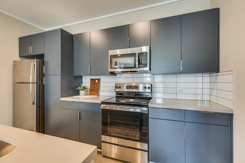 a kitchen with dark blue cabinets and stainless steel appliances
