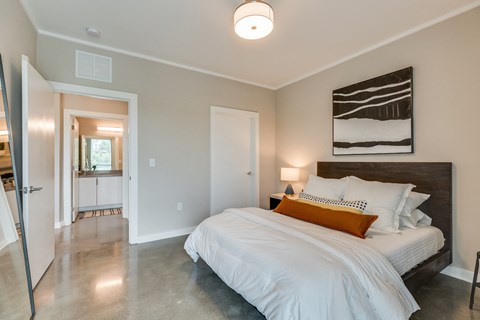 a bedroom with a large bed and a bathroom in the background