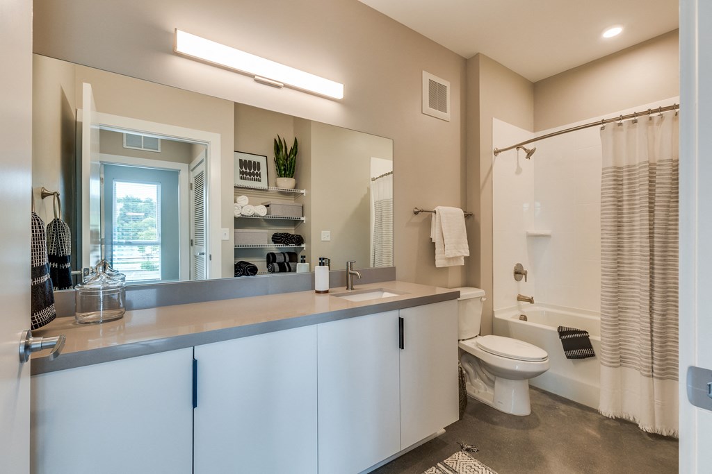 a bathroom with white cabinets and a large mirror