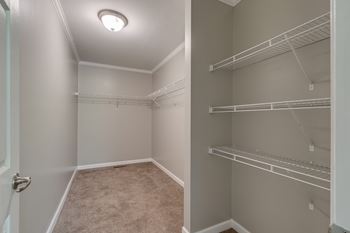 a spacious walk in closet in a new home with empty shelves