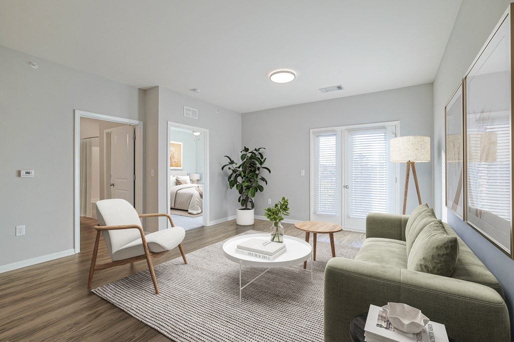 A living room with a grey couch, a white coffee table, a chair, and a potted plant.