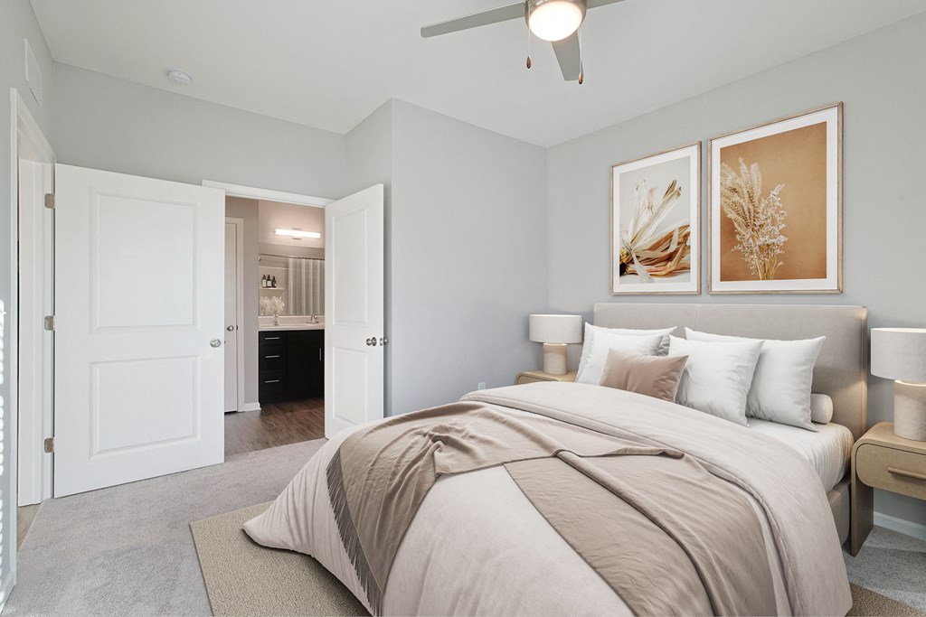 A bedroom with a large bed and two framed pictures on the wall.