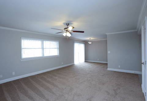 A room with a ceiling fan and carpeted floor.
