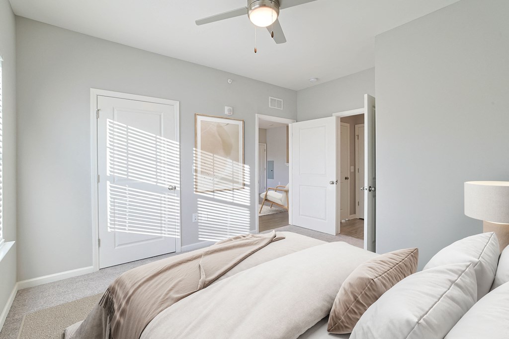 A bedroom with a bed, a ceiling fan, and a window with blinds.