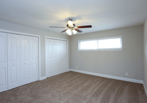 A room with a ceiling fan and two doors.
