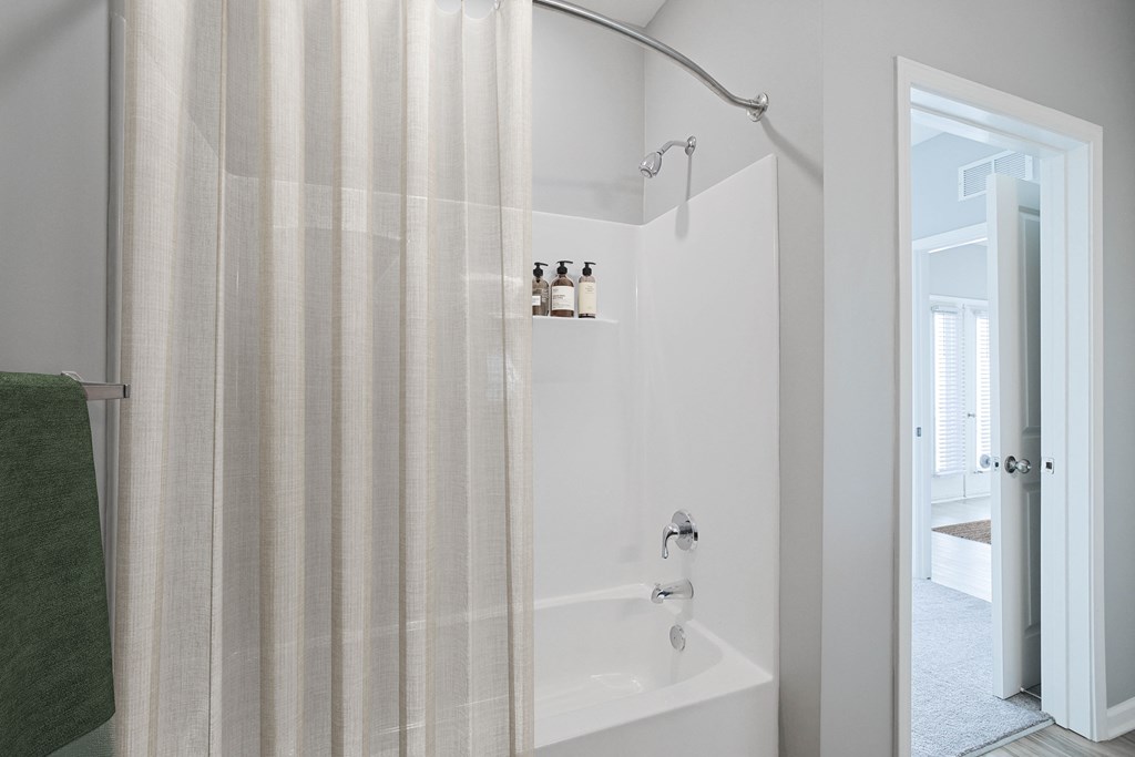 A white bathroom with a green towel hanging on the side.