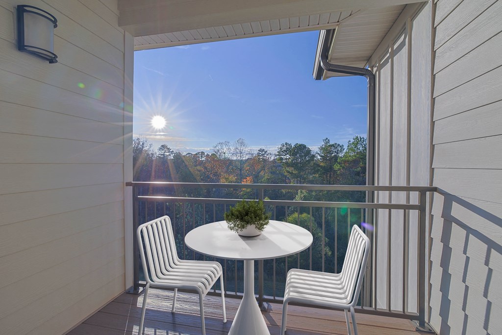 A balcony with a table and chairs overlooking a forest.