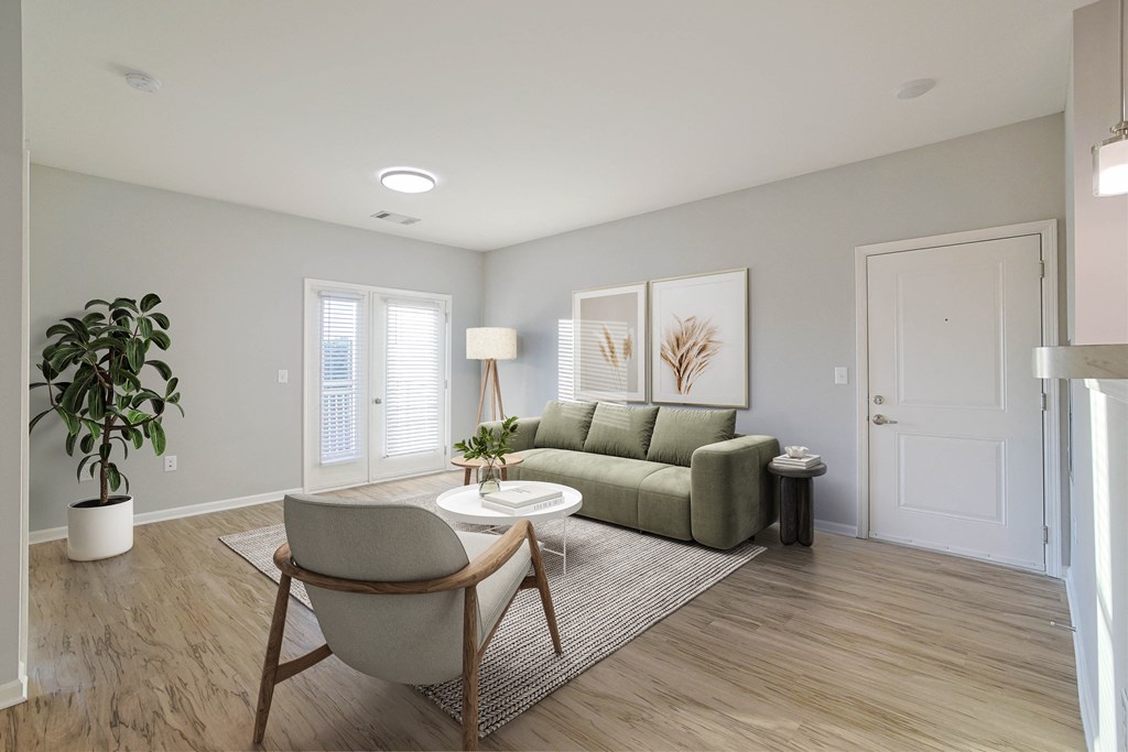 A living room with a green couch, a chair, and a potted plant.